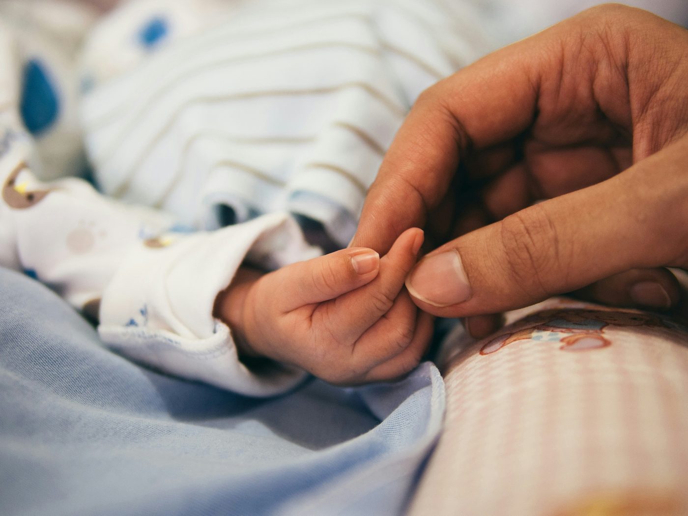 Newborn baby gently holding a parent's finger
