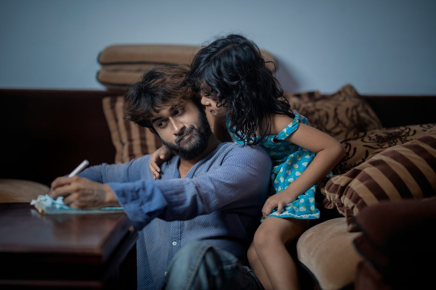 Father and daughter coloring together on the couch