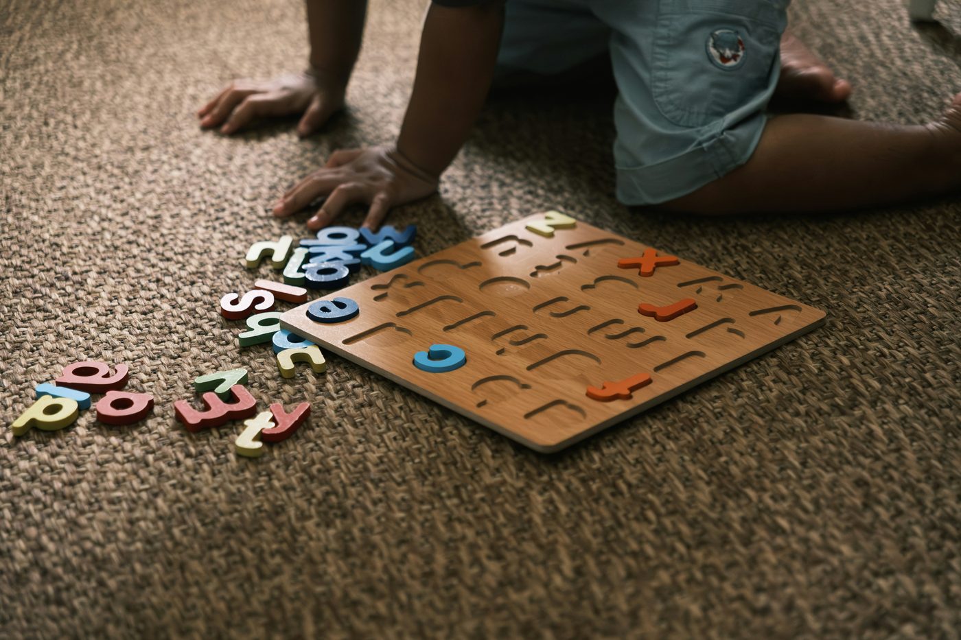 Young child kneeling on the floor completing a wooden puzzle